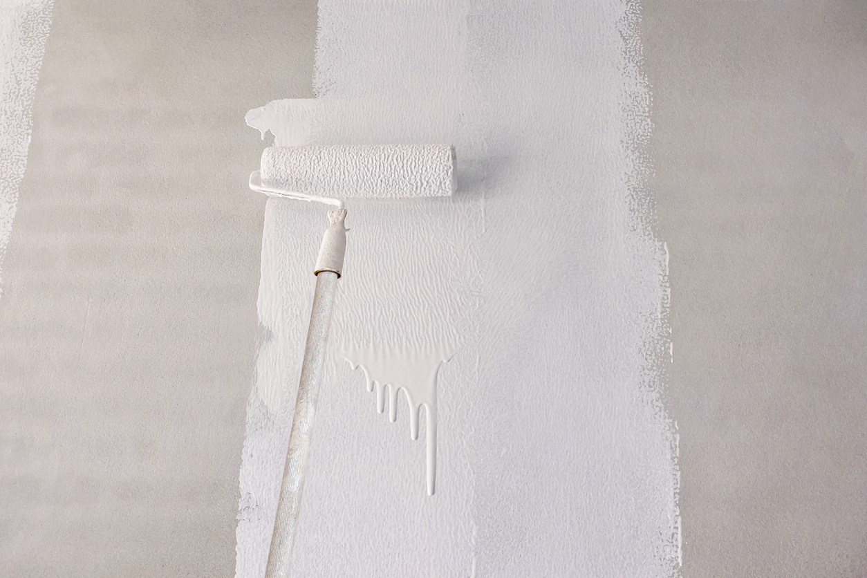 Painting primer white color on concrete wall with long handle roller brush in a San Ramon, CA home