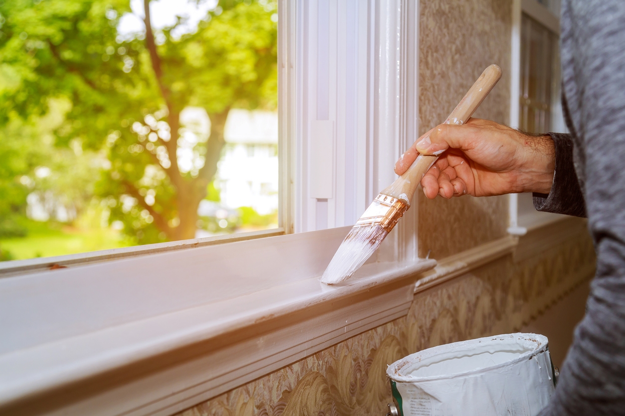 Man painting window trim at home, close-up