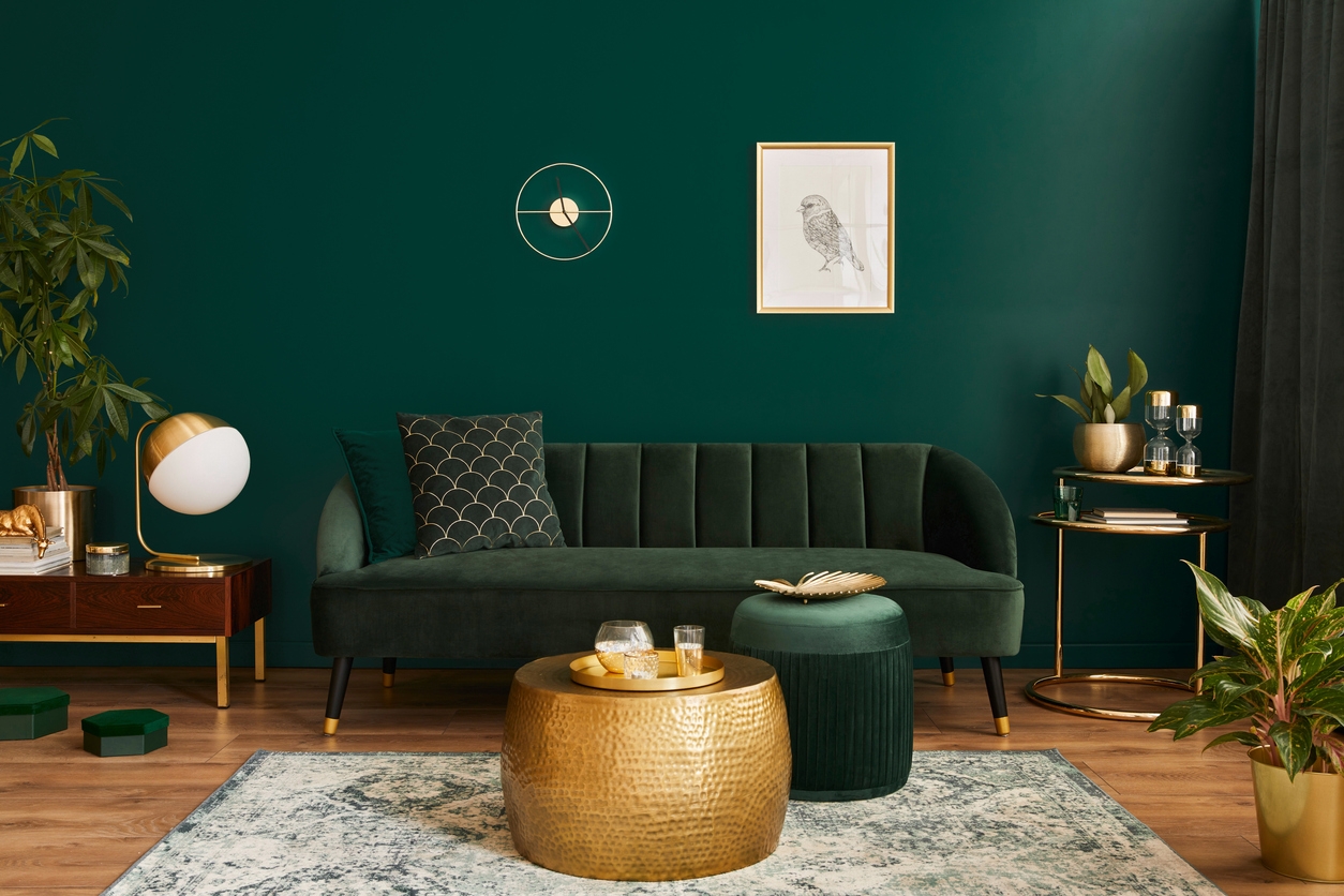 Luxury living room in house with modern interior design, green velvet sofa, coffee table, pouf, gold decoration, plant, lamp, carpet, mock up poster frame and elegant accessories. Template.